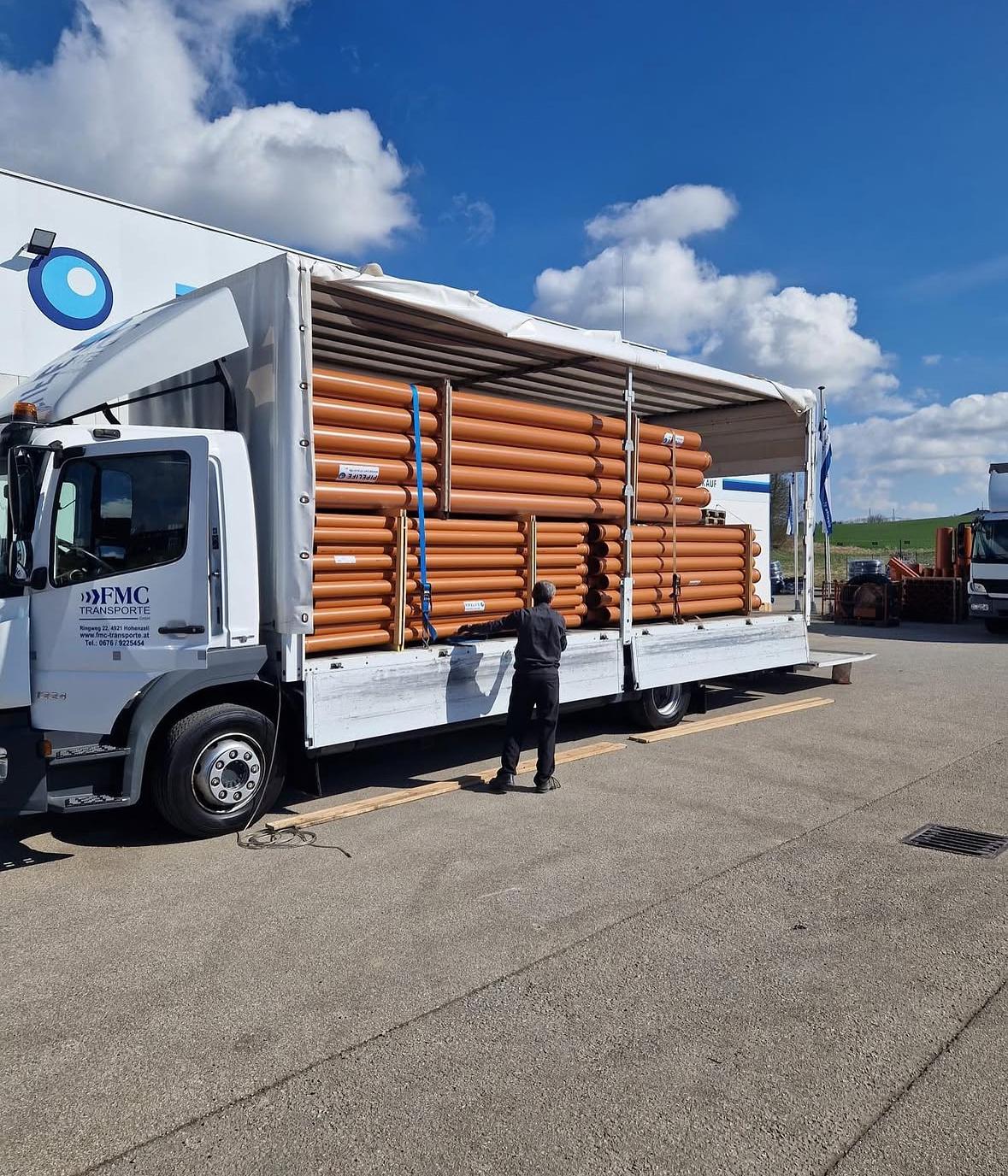 FMC Transporte GmbH — Plane-Lkw beim Beladen mit orangen Rohren
